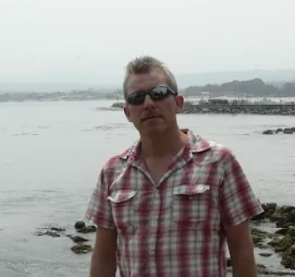 Portræt af Henrik Rassing ved havet i 2009 med solbriller og ternet skjorte